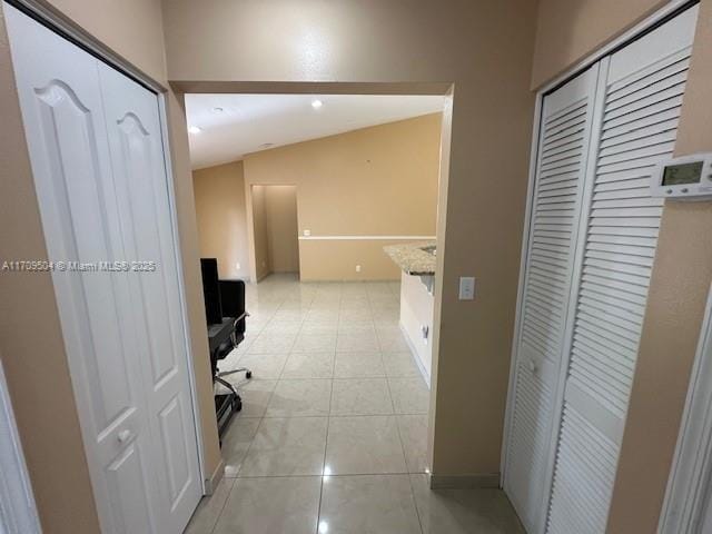 corridor with lofted ceiling and light tile patterned flooring