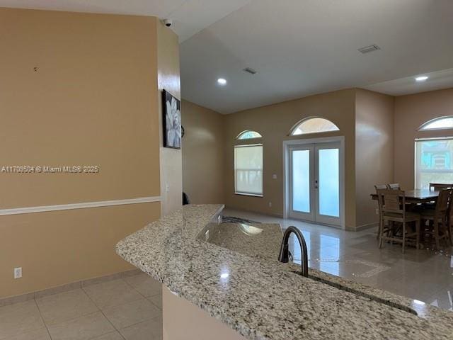 kitchen featuring french doors, light tile patterned flooring, and light stone counters