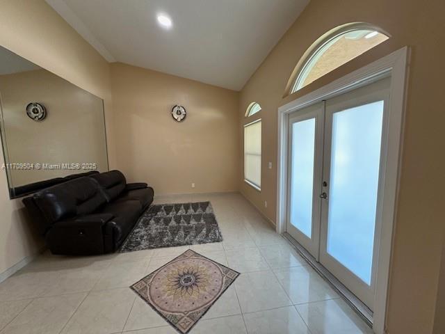 foyer with light tile patterned floors, vaulted ceiling, and french doors