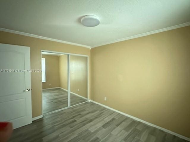 unfurnished bedroom with a closet, crown molding, and hardwood / wood-style flooring