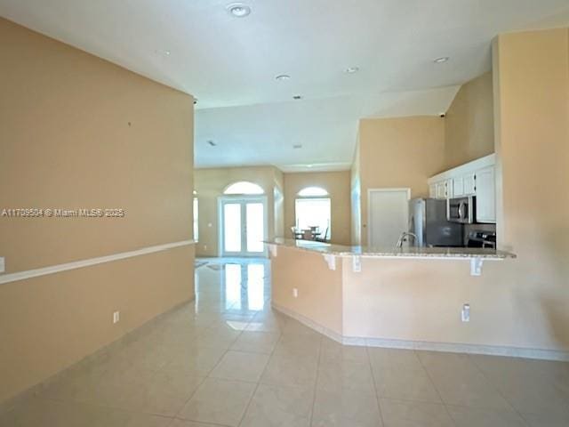 kitchen with kitchen peninsula, white cabinetry, appliances with stainless steel finishes, a breakfast bar area, and light tile patterned floors