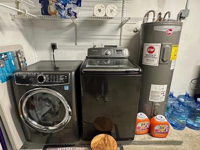 clothes washing area featuring washer and dryer and water heater