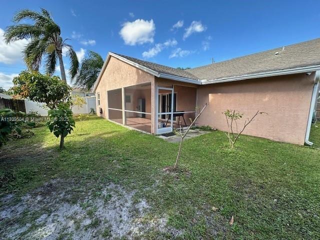 back of property with a lawn and a sunroom