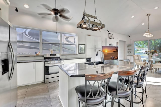 kitchen with sink, stainless steel appliances, pendant lighting, vaulted ceiling, and white cabinets