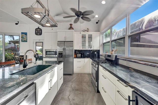 kitchen with a wealth of natural light, white cabinetry, appliances with stainless steel finishes, and vaulted ceiling