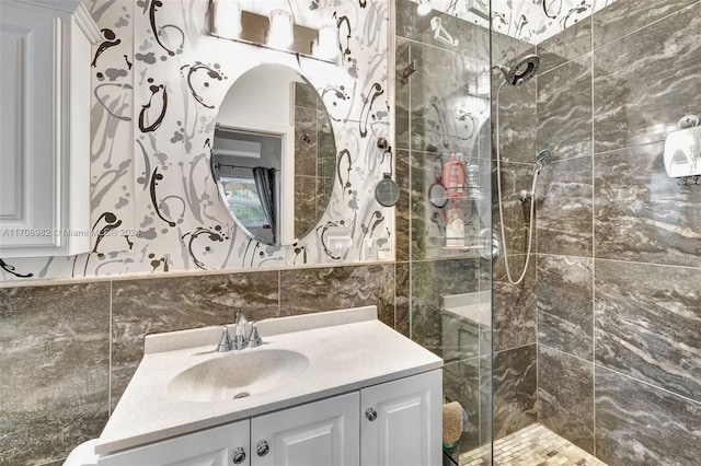 bathroom with a tile shower, vanity, and tile walls