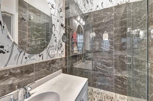 bathroom with a shower with door, vanity, and tile walls