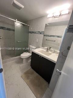 bathroom featuring tiled shower, vanity, and toilet