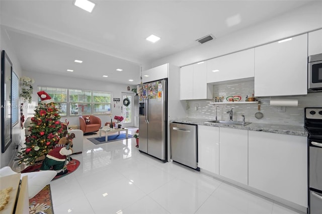 kitchen featuring sink, decorative backsplash, light stone countertops, white cabinetry, and stainless steel appliances