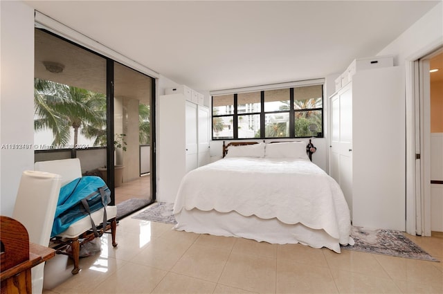 bedroom with light tile patterned floors, a closet, and a wall of windows