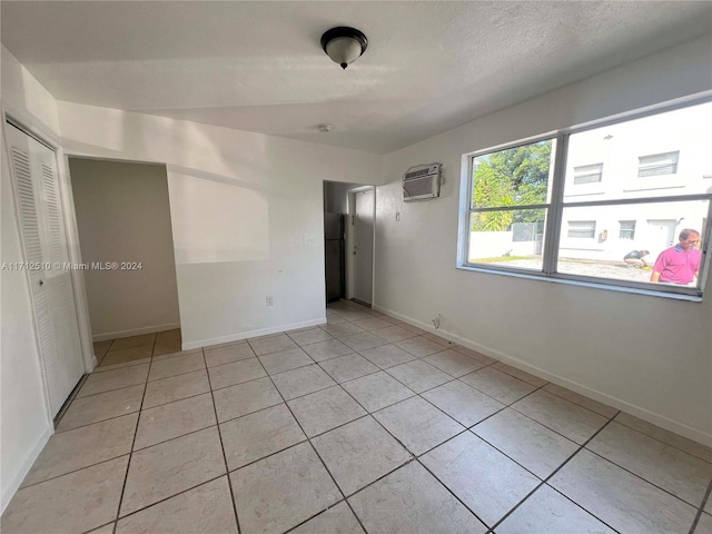 empty room featuring an AC wall unit and light tile patterned flooring