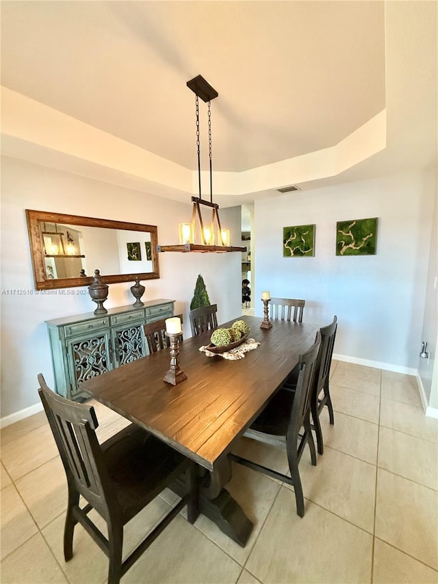 tiled dining space featuring a raised ceiling