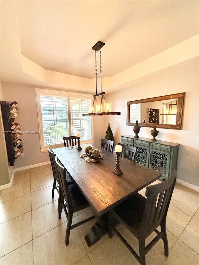 tiled dining space featuring a raised ceiling