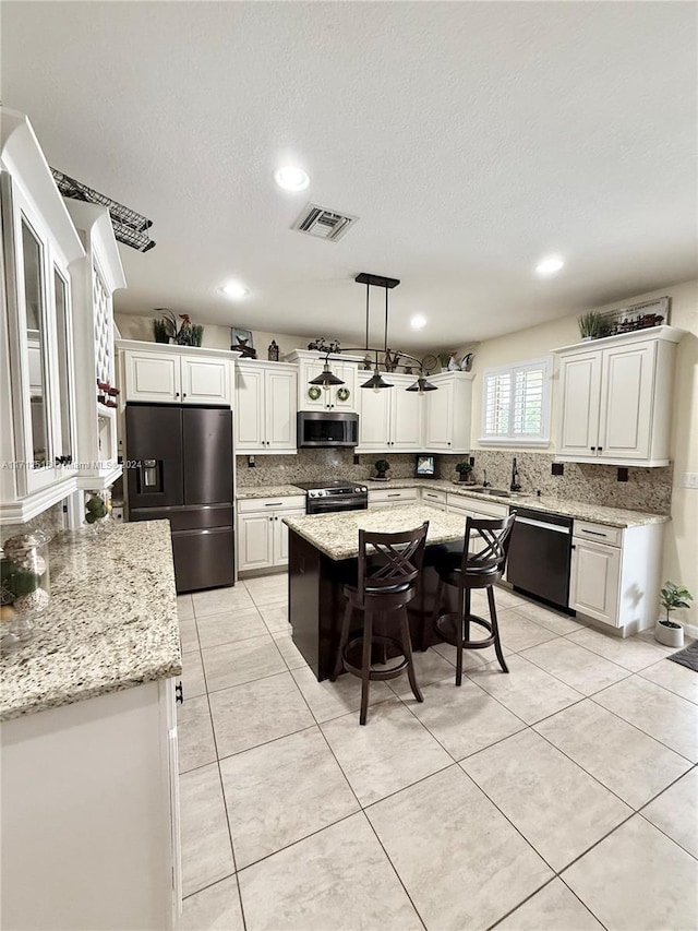 kitchen featuring light stone countertops, a breakfast bar, stainless steel appliances, pendant lighting, and a center island