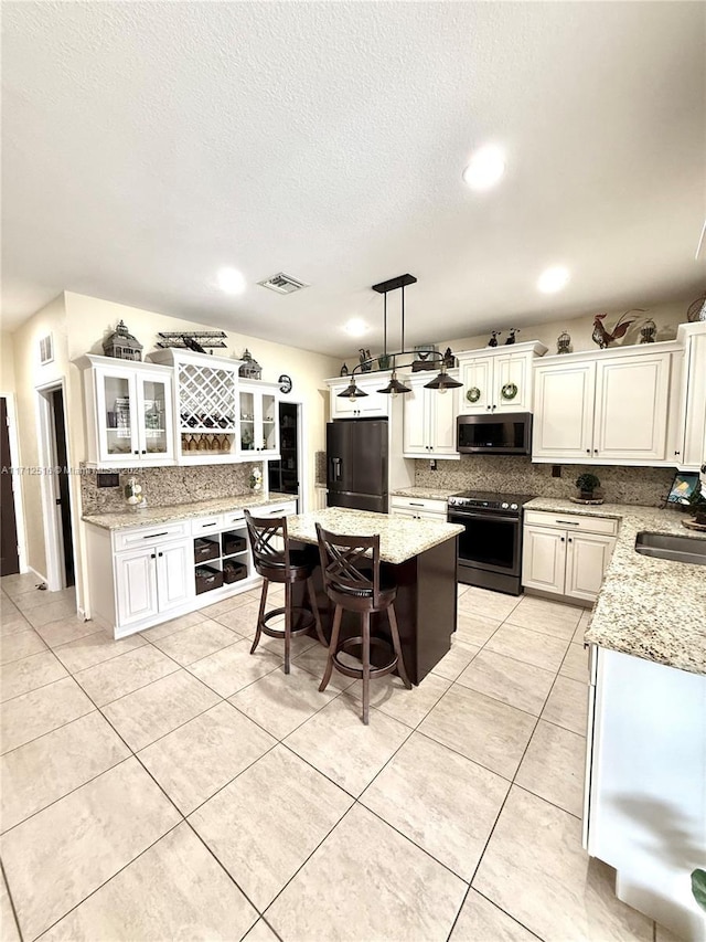 kitchen with appliances with stainless steel finishes, a center island, white cabinetry, and pendant lighting