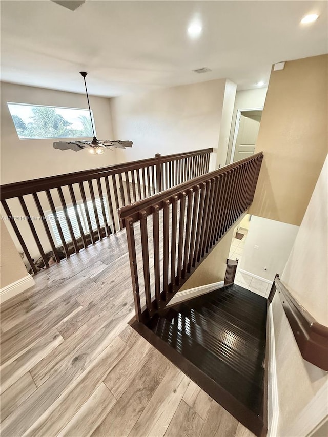 staircase with hardwood / wood-style floors and ceiling fan