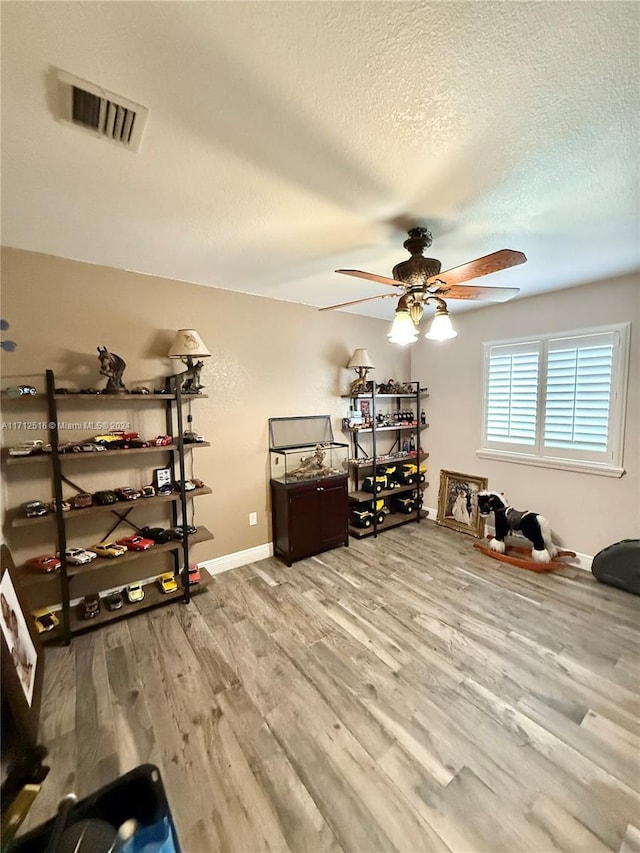 home office featuring wood-type flooring, a textured ceiling, and ceiling fan