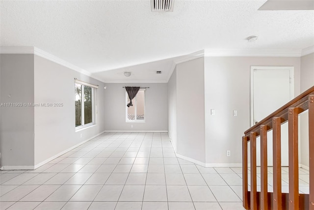 tiled empty room with a textured ceiling and ornamental molding