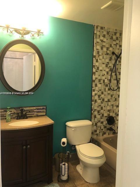 full bathroom with tile patterned floors, vanity, tiled shower / bath combo, and toilet