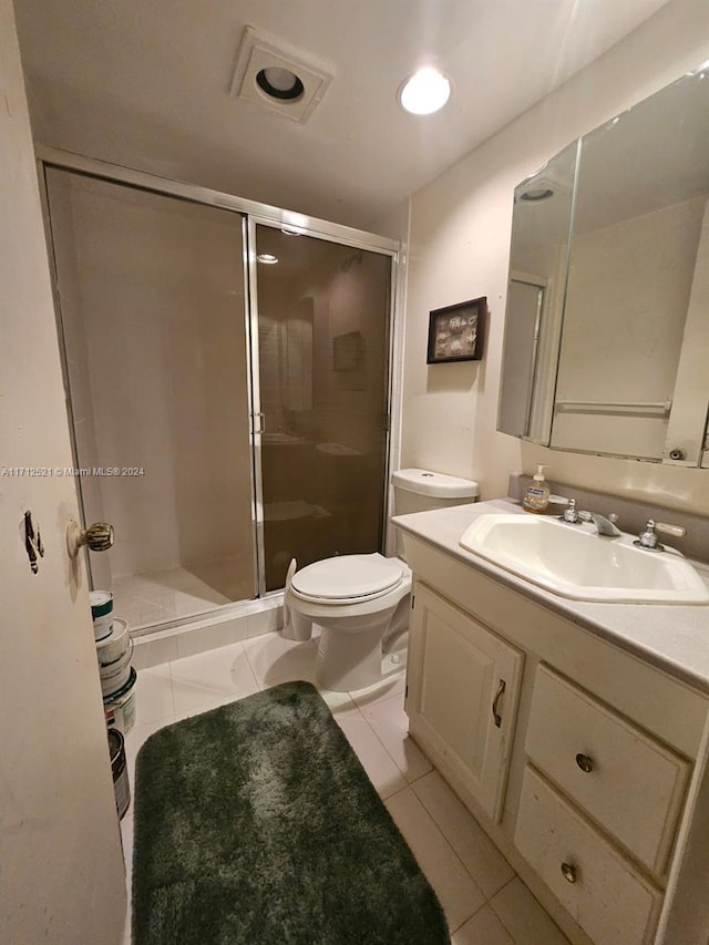 bathroom with tile patterned floors, vanity, a shower with shower door, and toilet