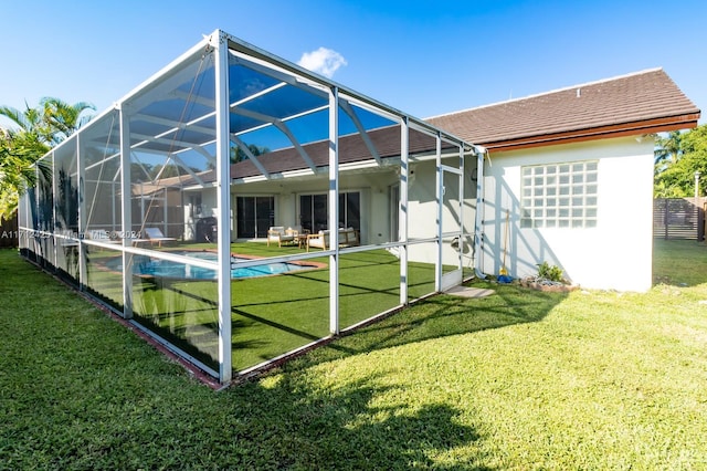 rear view of property featuring glass enclosure, a yard, and a patio