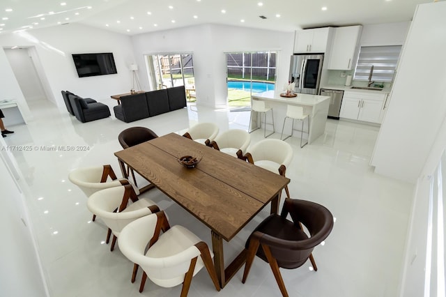 dining space featuring light tile patterned floors, vaulted ceiling, and sink