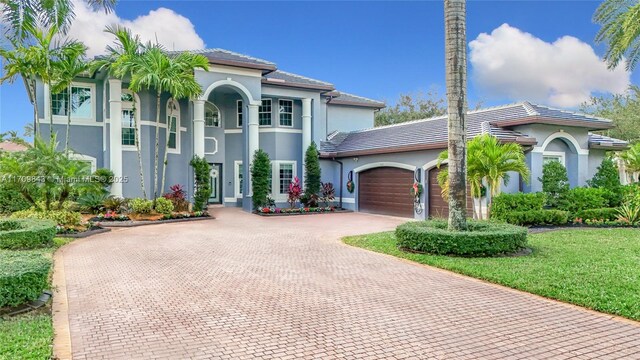 mediterranean / spanish house with a garage and a front lawn