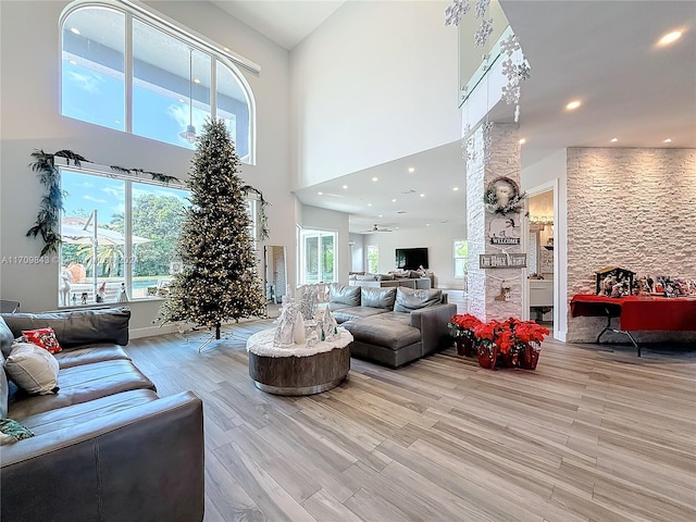 living room featuring ceiling fan, light hardwood / wood-style floors, and a high ceiling