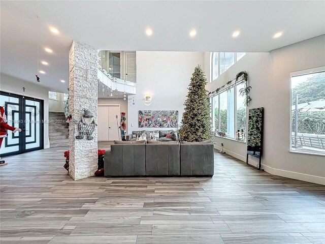 unfurnished living room with french doors, light wood-type flooring, and a healthy amount of sunlight