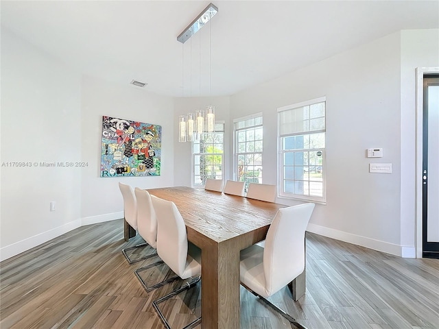 dining area with hardwood / wood-style flooring and an inviting chandelier