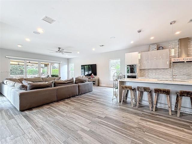 living room featuring a wealth of natural light, ceiling fan, and light hardwood / wood-style floors