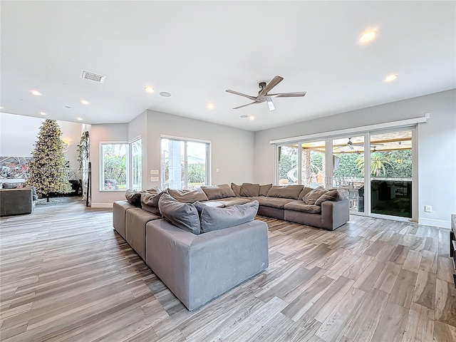 living room with a wealth of natural light, ceiling fan, and light hardwood / wood-style floors