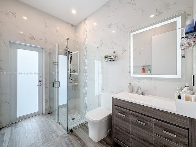 bathroom with an enclosed shower, vanity, toilet, and tile walls