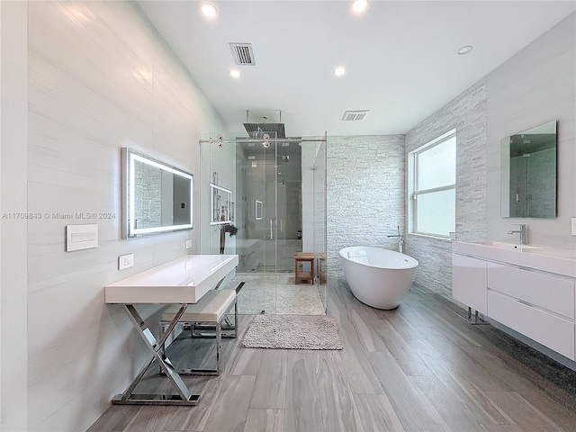 bathroom with shower with separate bathtub, vanity, tile walls, and wood-type flooring