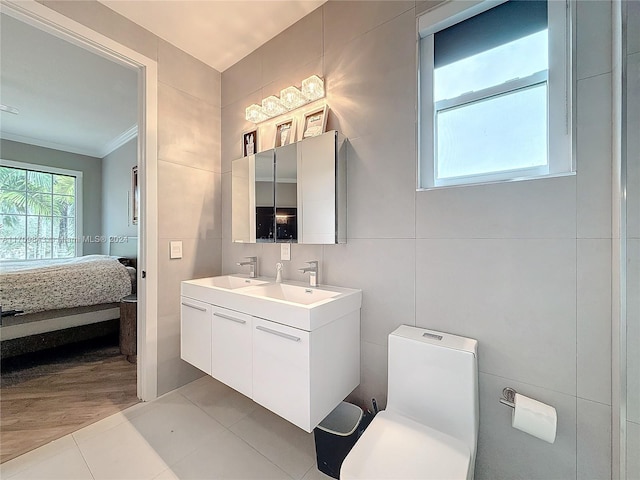 bathroom featuring tile patterned floors, ornamental molding, vanity, tile walls, and toilet