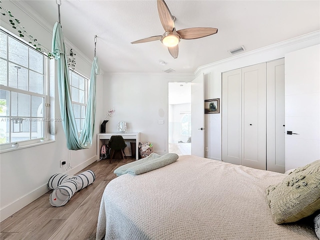 bedroom with a closet, ceiling fan, light hardwood / wood-style flooring, and ornamental molding