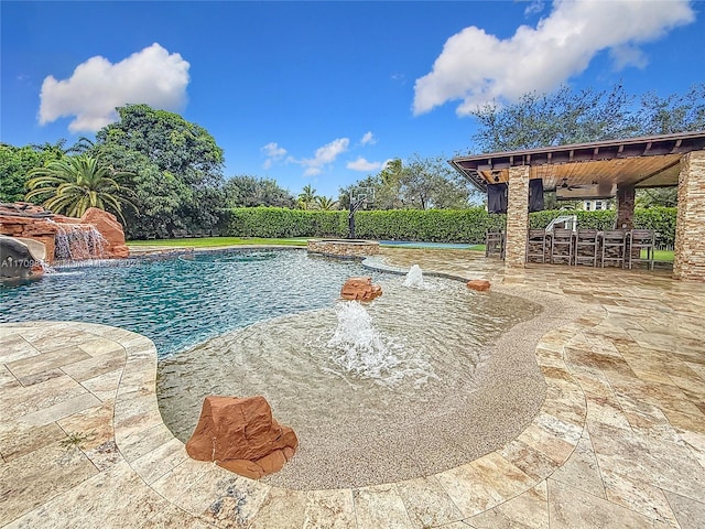 view of swimming pool featuring ceiling fan, a hot tub, pool water feature, a bar, and a patio