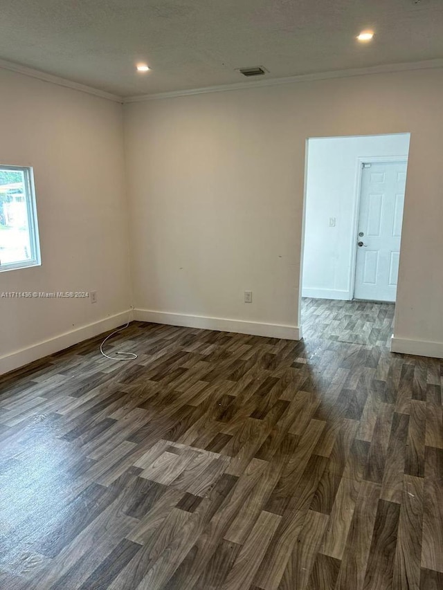 empty room featuring dark hardwood / wood-style flooring, ornamental molding, and a textured ceiling