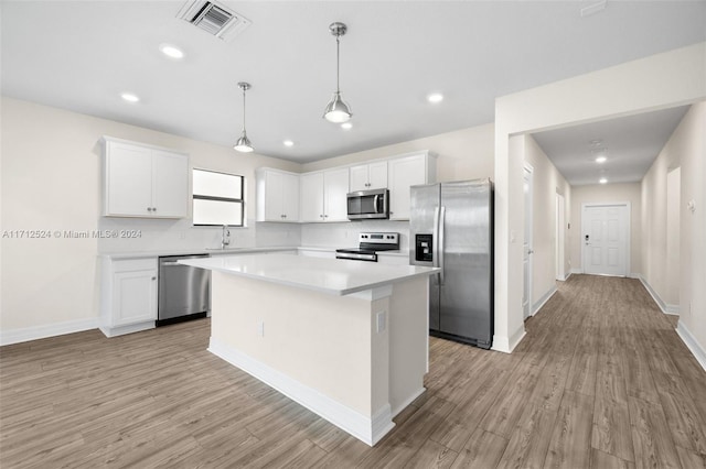 kitchen featuring white cabinets, stainless steel appliances, a kitchen island, and light hardwood / wood-style floors