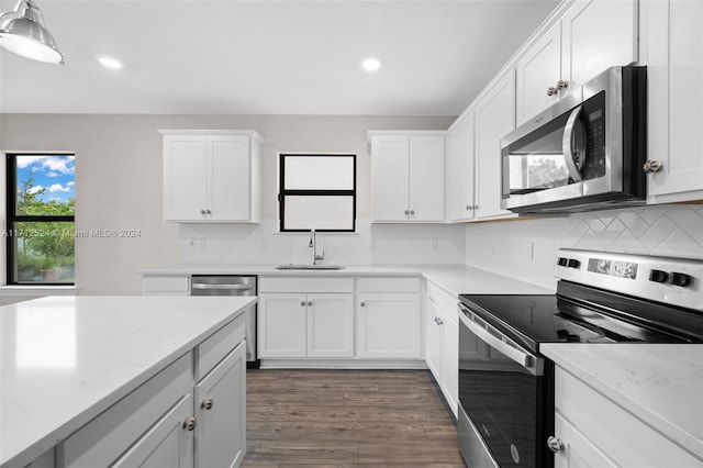 kitchen with light stone countertops, sink, dark wood-type flooring, stainless steel appliances, and white cabinets