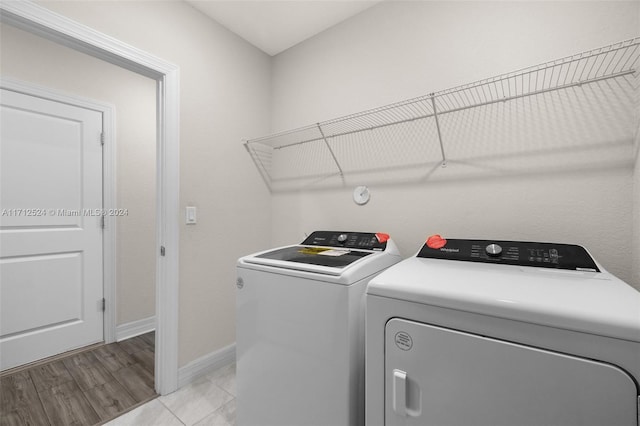 clothes washing area with independent washer and dryer and light wood-type flooring