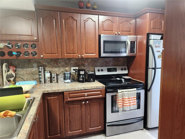 kitchen with decorative backsplash, stainless steel appliances, light stone counters, and sink