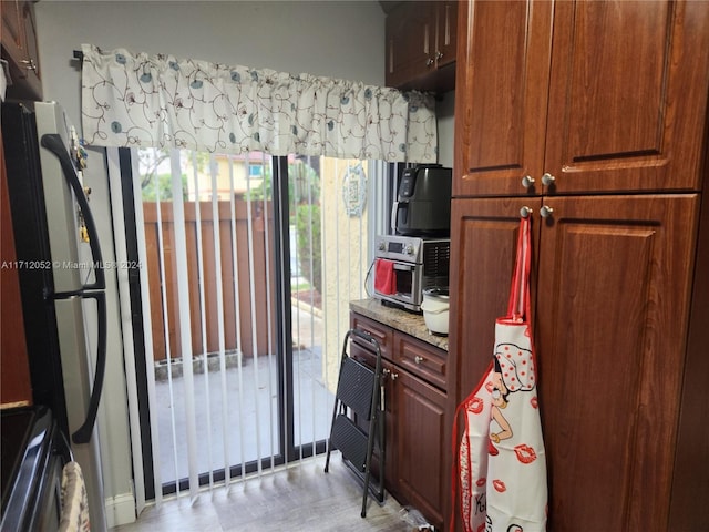 kitchen featuring stainless steel fridge, light stone counters, and range