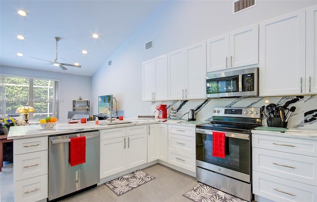 kitchen with ceiling fan, backsplash, kitchen peninsula, white cabinets, and appliances with stainless steel finishes