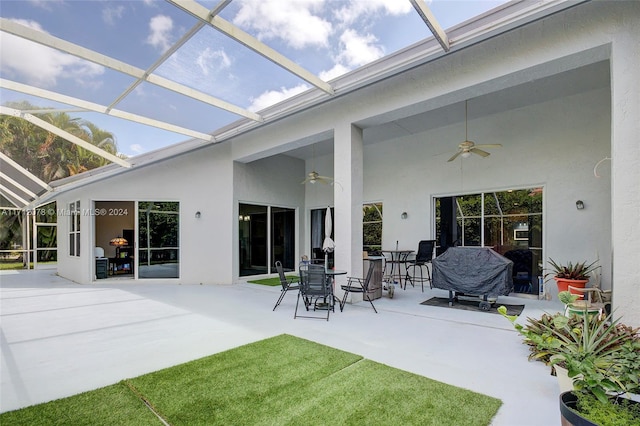 back of house featuring glass enclosure, ceiling fan, and a patio