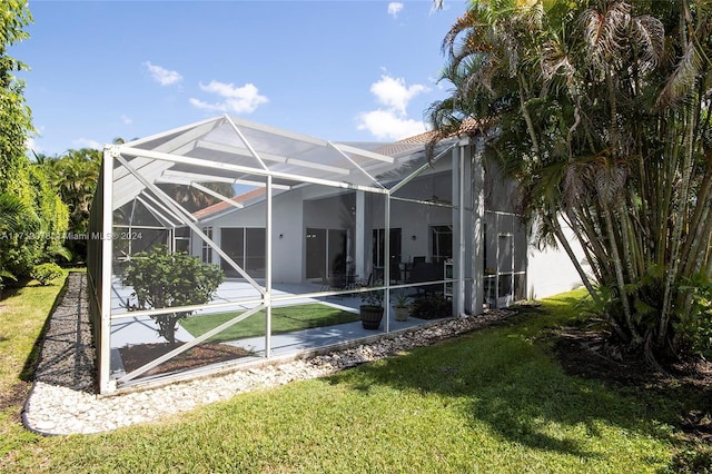 rear view of property featuring a patio area, a lanai, and a yard