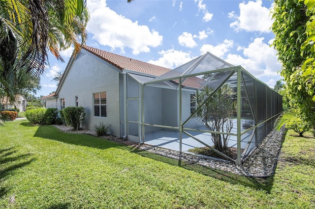 back of house featuring glass enclosure, a patio area, and a yard