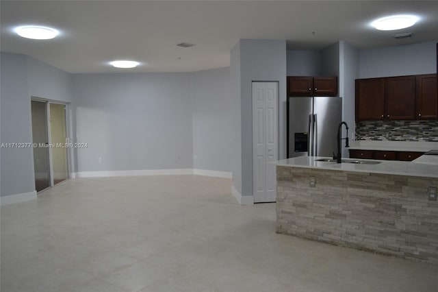 kitchen with stainless steel fridge with ice dispenser, dark brown cabinetry, backsplash, and sink