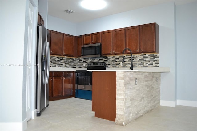 kitchen with sink, kitchen peninsula, decorative backsplash, light tile patterned floors, and appliances with stainless steel finishes