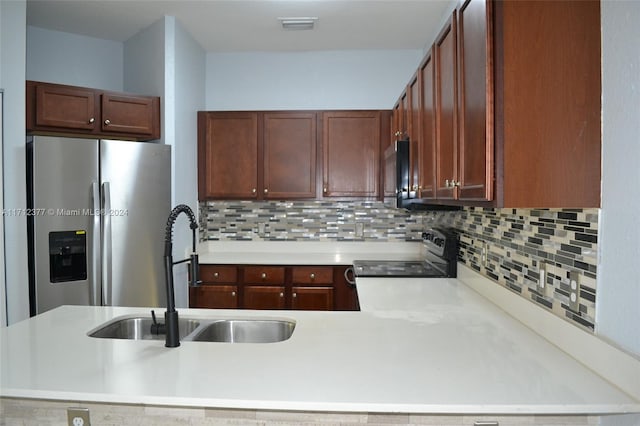 kitchen featuring kitchen peninsula, appliances with stainless steel finishes, tasteful backsplash, and sink